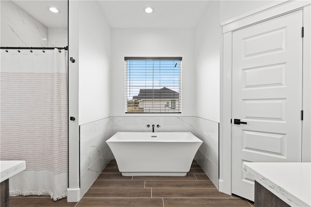 bathroom featuring plus walk in shower, vanity, hardwood / wood-style flooring, and tile walls