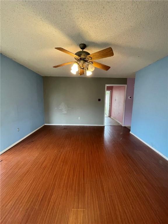 2418 Vialoux Dr, Corpus Christi, TX 78418 - empty room featuring a ceiling fan, baseboards, wood finished floors, and a textured ceiling
