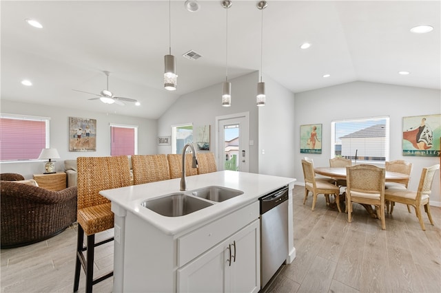 kitchen with light hardwood / wood-style floors, hanging light fixtures, sink, a kitchen island with sink, and stainless steel dishwasher