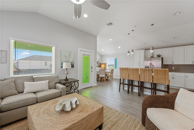 living room featuring light wood-type flooring, vaulted ceiling, and ceiling fan