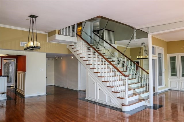 stairs with crown molding, a towering ceiling, and hardwood / wood-style flooring