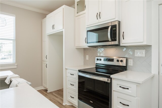 kitchen featuring light hardwood / wood-style flooring, ornamental molding, backsplash, white cabinetry, and appliances with stainless steel finishes