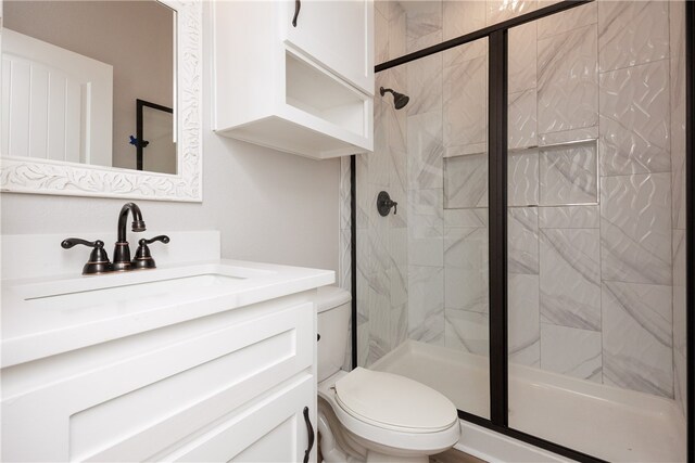 bathroom with a shower with door, vanity, and toilet