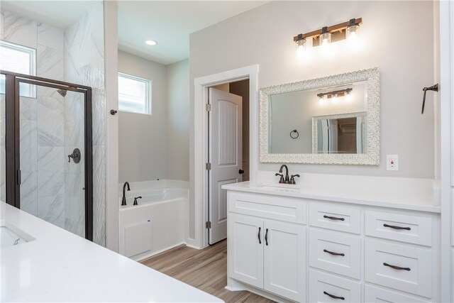 bathroom with vanity, hardwood / wood-style flooring, and plus walk in shower