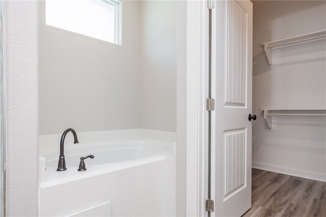 bathroom with a bath and hardwood / wood-style flooring