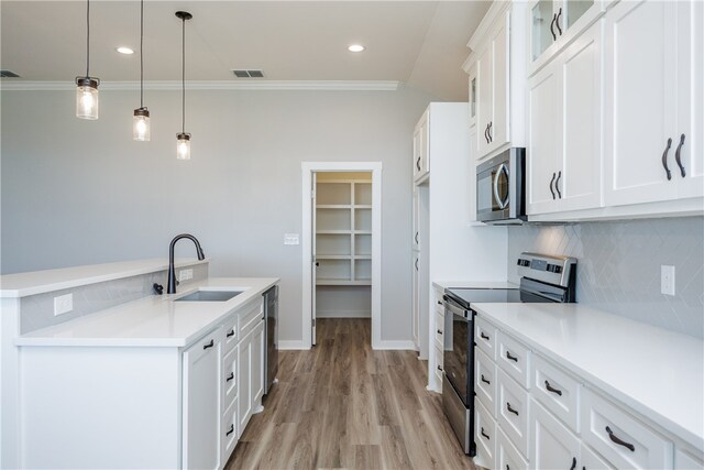 kitchen with white cabinets, light hardwood / wood-style flooring, sink, pendant lighting, and appliances with stainless steel finishes