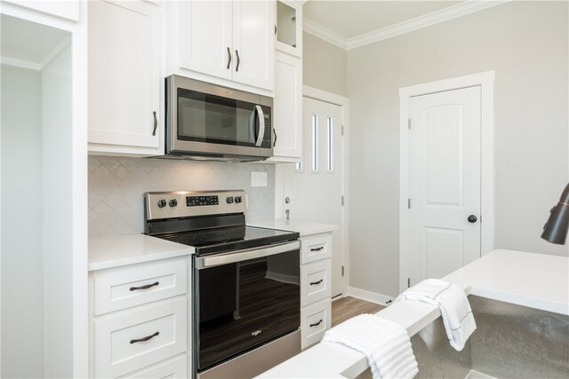 kitchen with white cabinets, hardwood / wood-style flooring, tasteful backsplash, ornamental molding, and appliances with stainless steel finishes