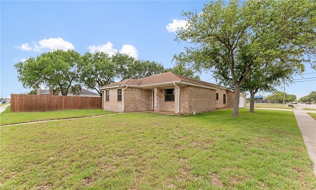 view of side of home with brick siding, fence, and a yard