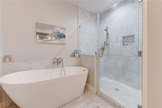 bathroom with marble finish floor, a soaking tub, and a shower stall