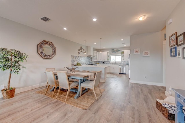 dining room with light wood-style floors, baseboards, and visible vents