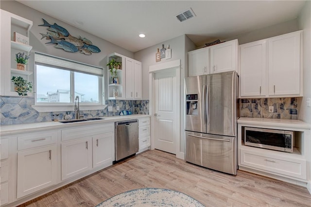 kitchen featuring open shelves, visible vents, appliances with stainless steel finishes, white cabinets, and a sink