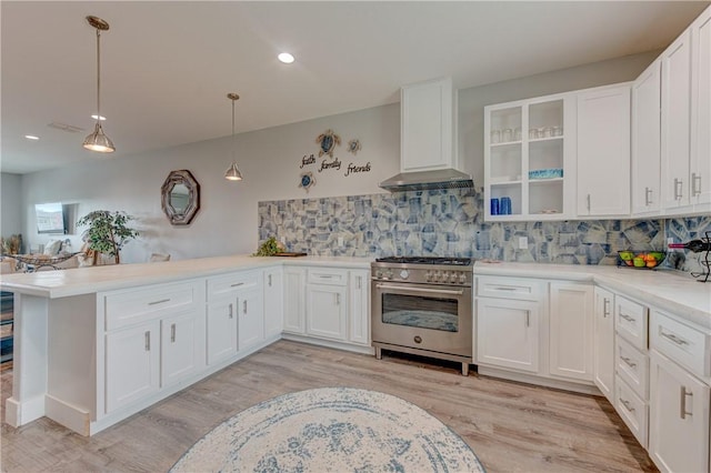 kitchen featuring decorative backsplash, high end stainless steel range, a peninsula, wall chimney range hood, and white cabinetry