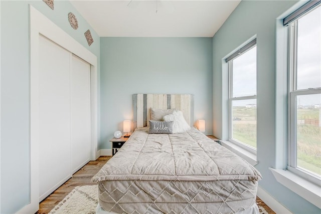 bedroom with a closet, baseboards, and wood finished floors