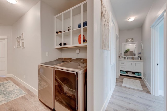 washroom featuring light wood finished floors, laundry area, baseboards, and separate washer and dryer