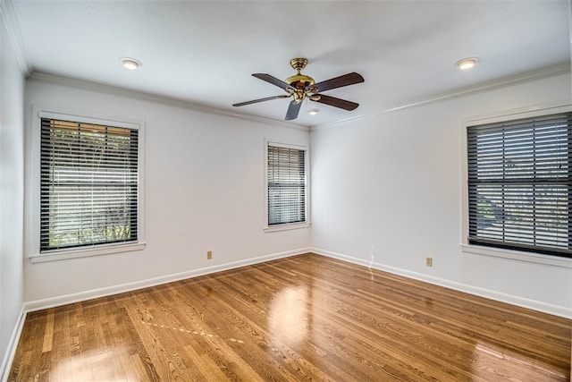 empty room with plenty of natural light, crown molding, baseboards, and wood finished floors