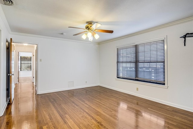 spare room with ceiling fan, crown molding, baseboards, and wood finished floors