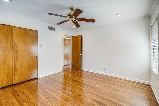 unfurnished bedroom featuring light wood finished floors, baseboards, visible vents, and crown molding