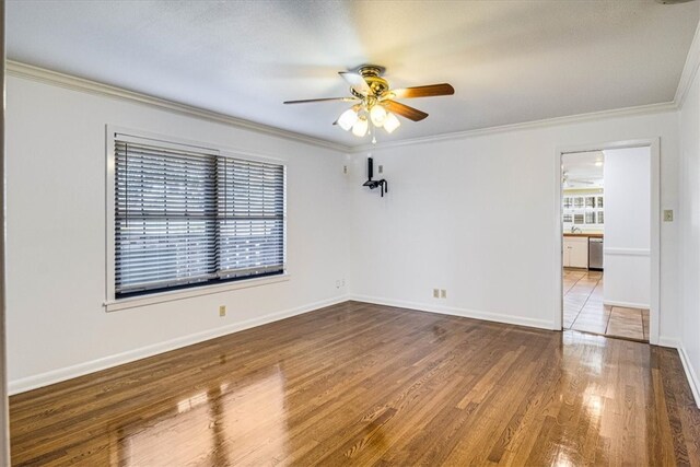 spare room with ornamental molding, a ceiling fan, baseboards, and wood finished floors