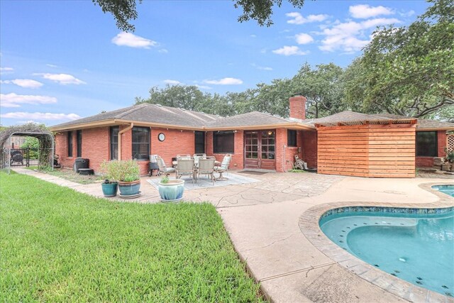 back of house featuring a yard, a patio area, a chimney, and brick siding