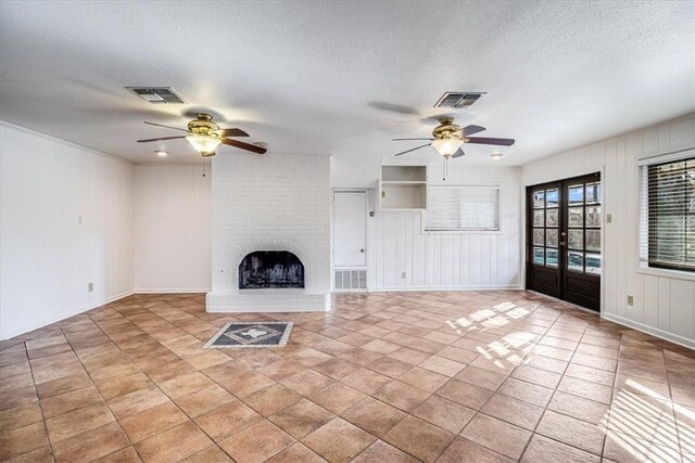 unfurnished living room with a brick fireplace, visible vents, a ceiling fan, and french doors