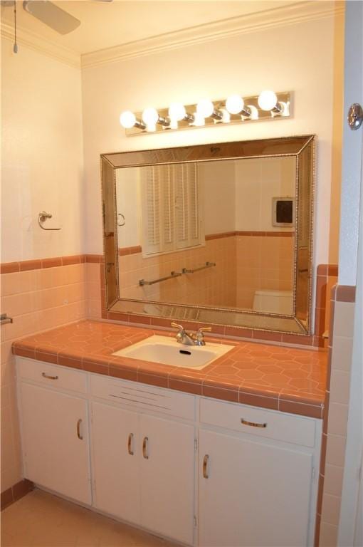 bathroom featuring wainscoting, crown molding, tile walls, and vanity