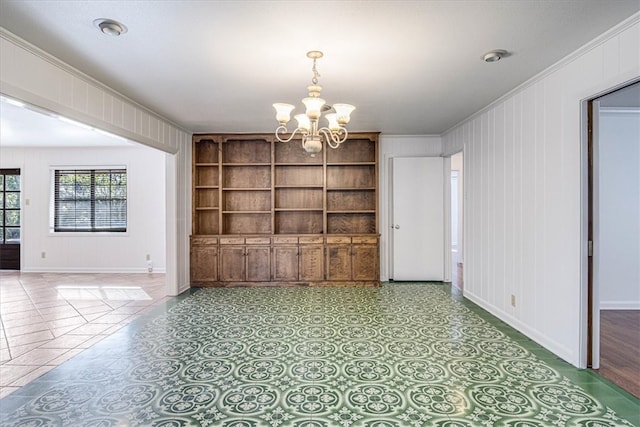 unfurnished room featuring crown molding, baseboards, built in features, and an inviting chandelier