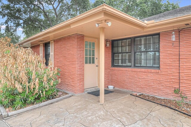 doorway to property with a patio and brick siding