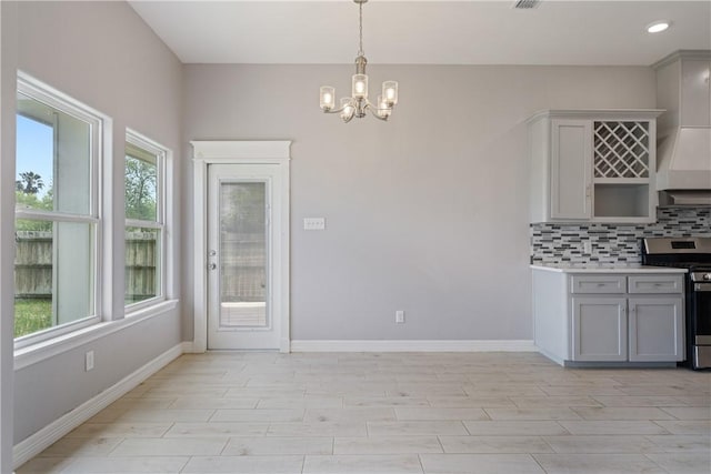 1706 Kentucky Derby Dr, Corpus Christi, TX 78417 - kitchen featuring gray cabinets, stainless steel gas stove, baseboards, decorative backsplash, and an inviting chandelier