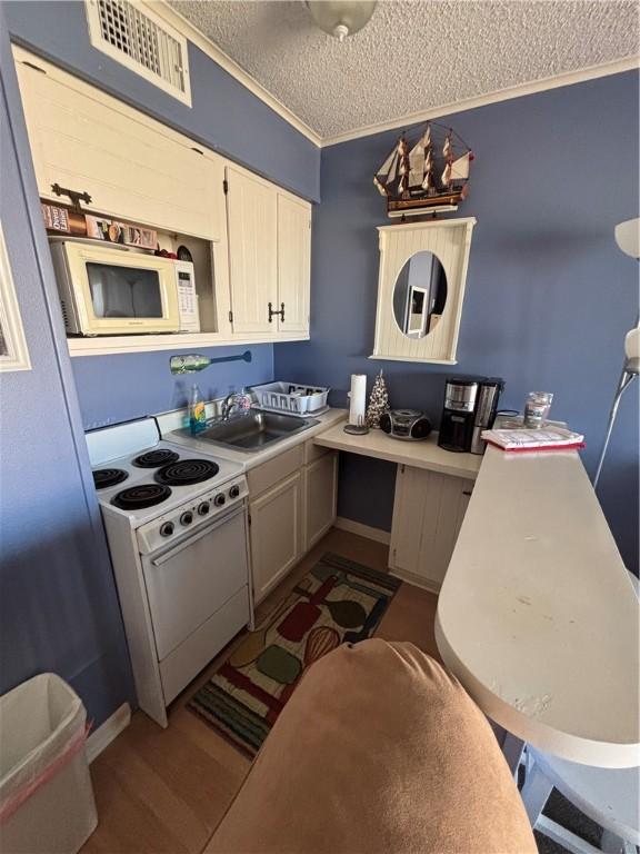 3938 Surfside Blvd Unit 2235, Corpus Christi, TX 78402 - kitchen featuring white appliances, a textured ceiling, ornamental molding, wood finished floors, and light countertops