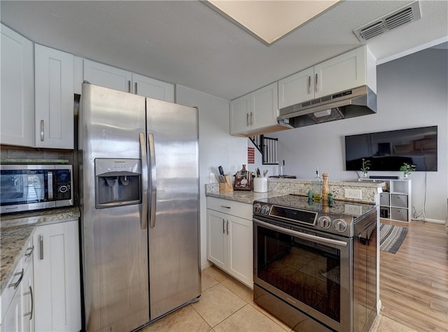 kitchen featuring visible vents, white cabinets, appliances with stainless steel finishes, light stone countertops, and under cabinet range hood