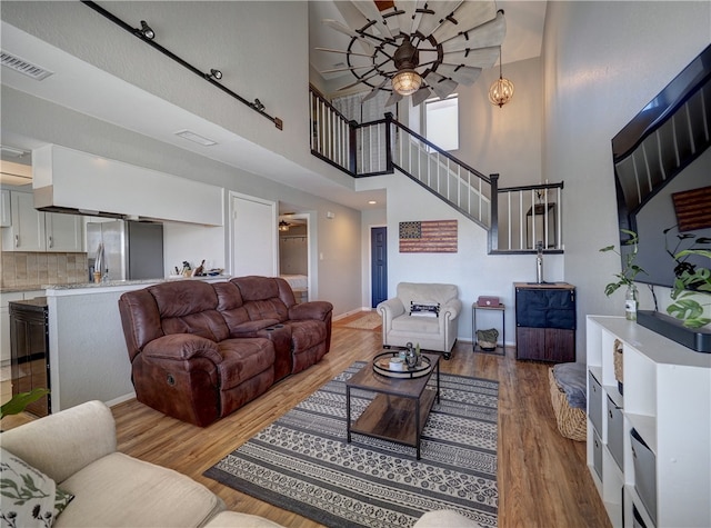 living area featuring visible vents, ceiling fan, stairway, and wood finished floors