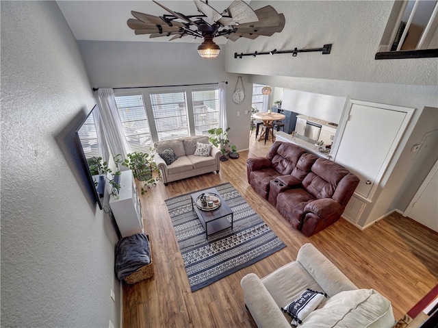 living room with baseboards, wood finished floors, and a textured wall