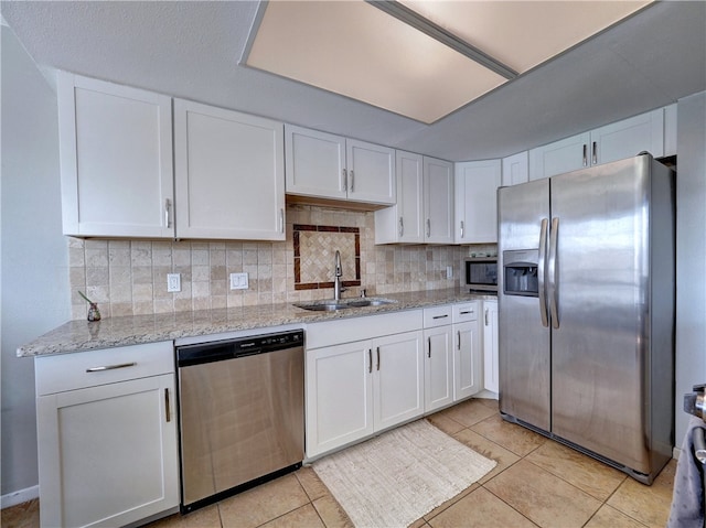 kitchen featuring stainless steel appliances, backsplash, a sink, and white cabinetry