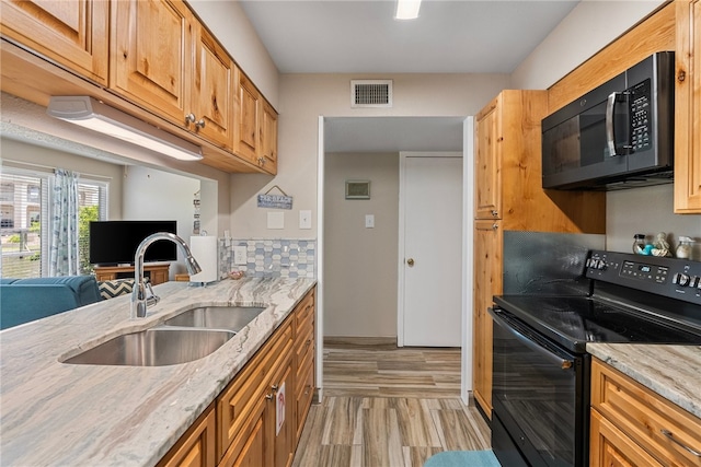 kitchen featuring black electric range oven, light hardwood / wood-style flooring, sink, and light stone counters