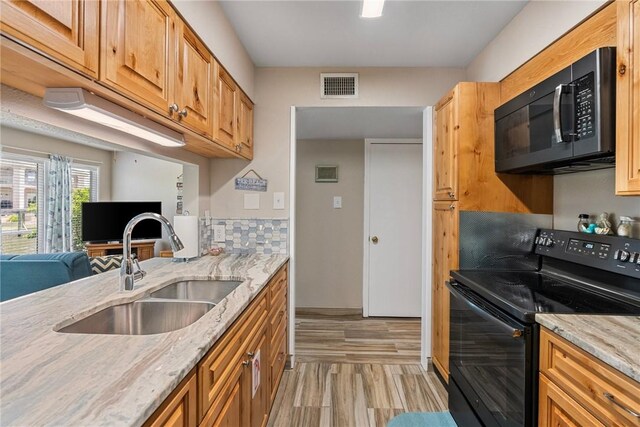 14300 Aloha St N Unit 139, Corpus Christi, TX 78418 - kitchen with black appliances, light stone counters, open floor plan, light wood-type flooring, and tasteful backsplash