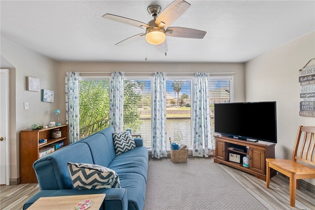 living room with light wood-type flooring, a textured ceiling, and ceiling fan