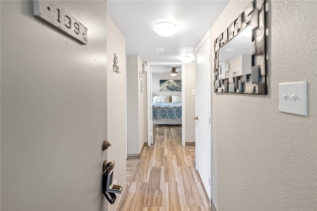 hallway featuring light wood-type flooring and a textured ceiling