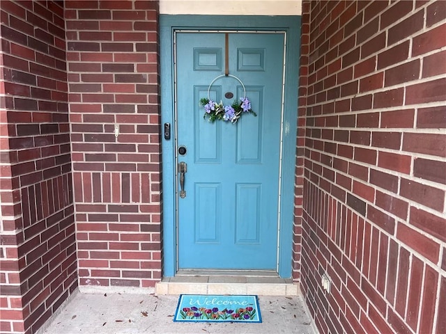 view of exterior entry featuring brick siding