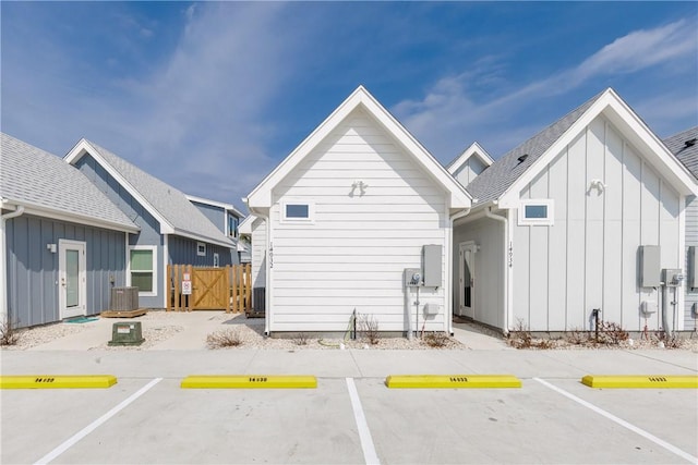 back of property with uncovered parking, fence, and board and batten siding