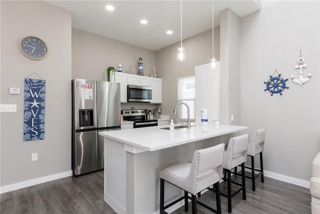 kitchen with a kitchen breakfast bar, a peninsula, stainless steel appliances, white cabinetry, and a sink