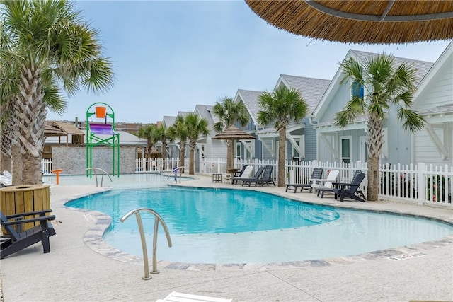 community pool with a patio area and fence