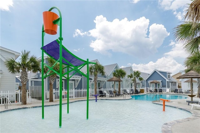 community pool with a patio area, fence, and a residential view