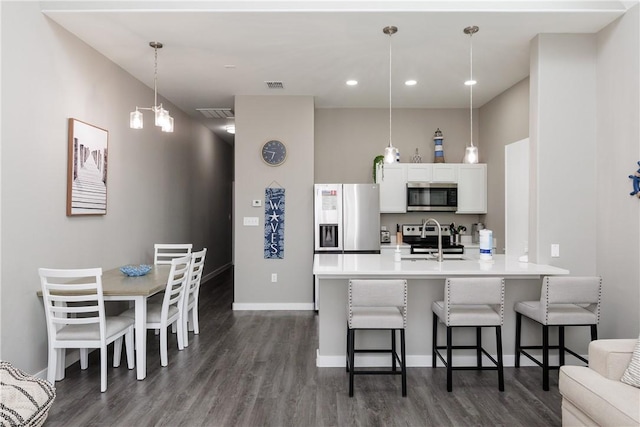 kitchen with visible vents, dark wood-style floors, a kitchen breakfast bar, stainless steel appliances, and white cabinetry