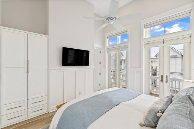 bedroom featuring a high ceiling, a wainscoted wall, access to exterior, a decorative wall, and french doors