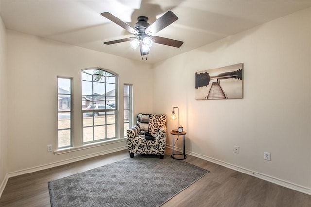 living area with dark wood-type flooring and ceiling fan