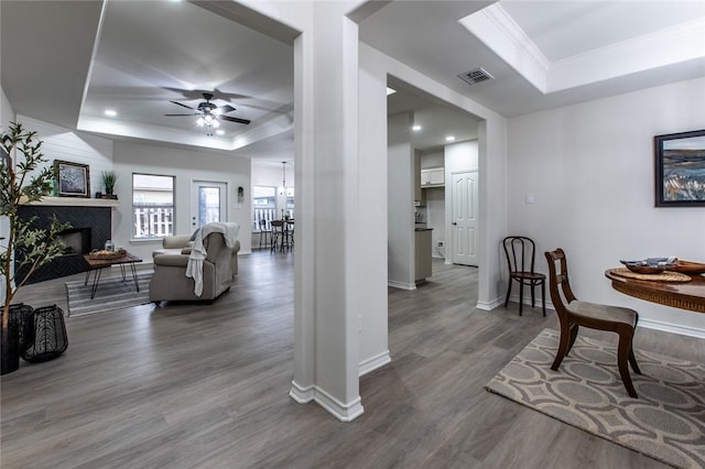 interior space featuring hardwood / wood-style flooring, ceiling fan, ornamental molding, and a raised ceiling