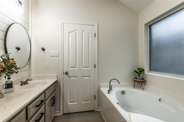 bathroom with a tub to relax in, vanity, and wood-type flooring