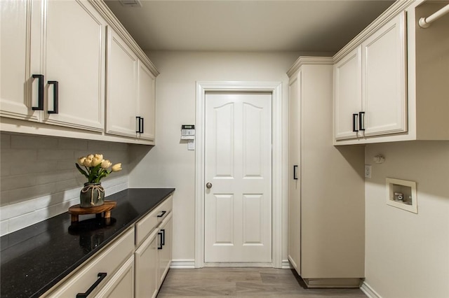 laundry area featuring washer hookup, light hardwood / wood-style flooring, and cabinets