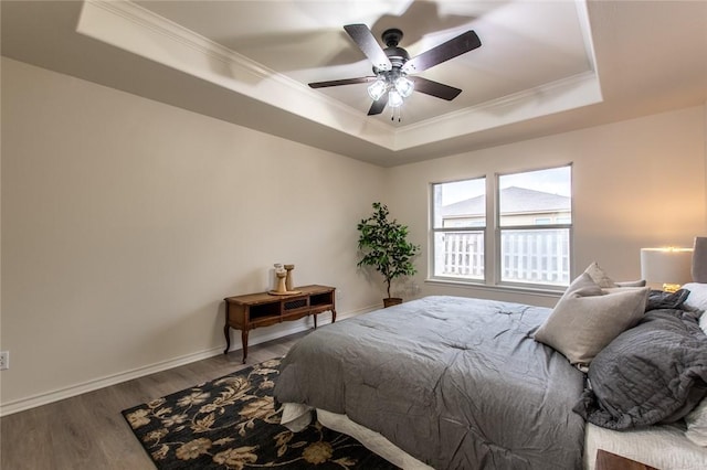 bedroom featuring ornamental molding, wood-type flooring, and a tray ceiling