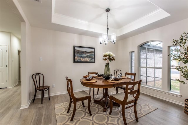 dining area featuring hardwood / wood-style flooring, a healthy amount of sunlight, and a raised ceiling